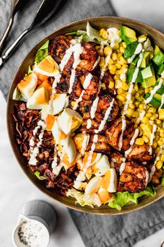 a salad with chicken, lettuce and dressing in a bowl on a table