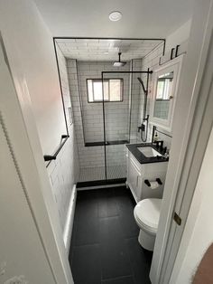 a bathroom with black and white tile flooring, toilet and shower stall in it