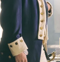 a close up of a person wearing a blue coat and holding a white object in his hand