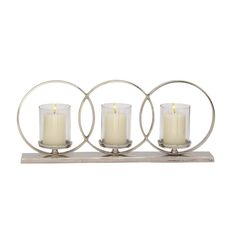 three candles sitting on top of each other in front of a metal holder with circles around them