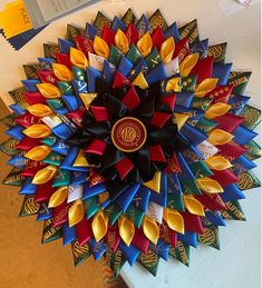 a close up of a colorful flower made out of ribbons on a table with other items in the background