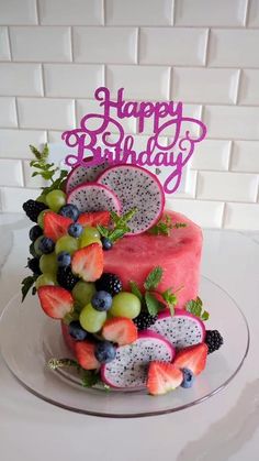 a birthday cake decorated with fruit and the words happy birthday on it's top