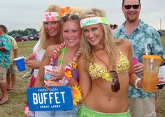 three women in bikinis and headbands holding drinks at a beach party with other people