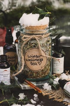 a glass jar filled with herbs sitting on top of a table next to other bottles