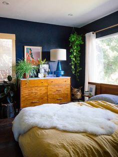 a bed room with a neatly made bed next to a window and a wooden dresser