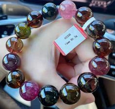 a person holding up a bracelet made out of glass beads with a price tag on it