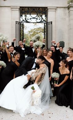 a bride and groom kissing in front of their wedding party