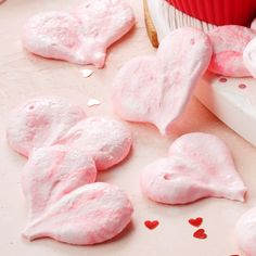 pink heart shaped marshmallows on a table next to a cupcake with frosting