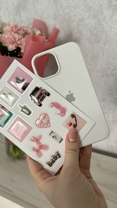 a person holding an iphone case with various stickers on the back and side of it