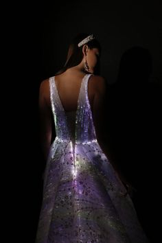 the back of a woman's dress is lit up in purple and white lights