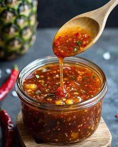 a spoon full of chili sauce on top of a cutting board