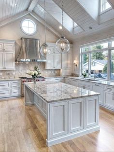 a large kitchen with white cabinets and marble counter tops, an island in the middle