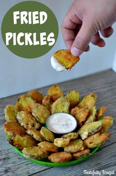 fried pickles on a green plate with dip in the middle and hand dipping sauce