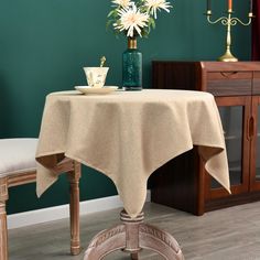 a dining room table with a vase of flowers on it and two candles in the background