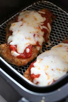 two meat patties covered in sauce and cheese on top of an air fryer