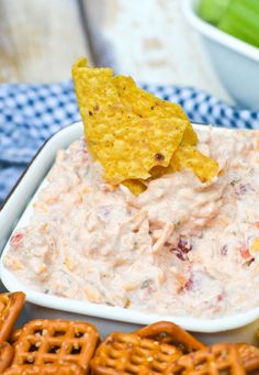 a bowl of dip with crackers and pretzels on the side