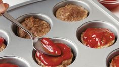 a person spooning ketchup out of a muffin tin