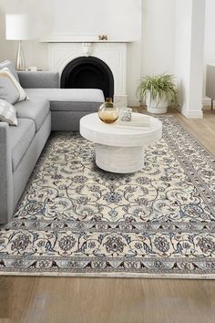 a living room with a couch, coffee table and rug on the floor in front of a fireplace