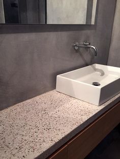 a white sink sitting on top of a counter next to a mirror and faucet