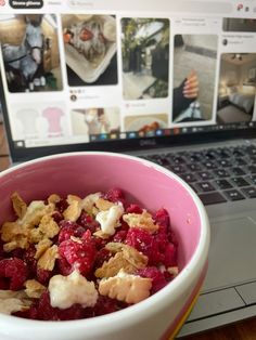 a bowl filled with fruit next to a laptop