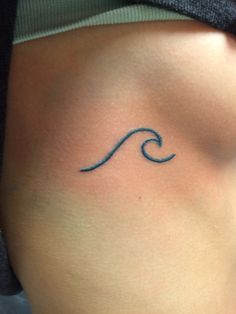 a woman's stomach with a small wave tattoo on it