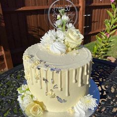 a three tiered cake with white flowers and butterflies on the top is sitting on a blue plate