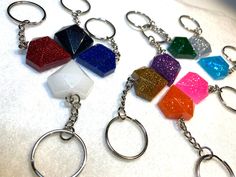 four different colored keychains are on a white surface and one has a metal ring