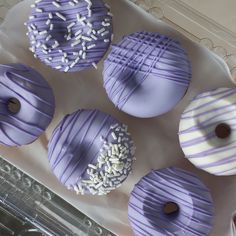 six donuts with purple frosting and sprinkles