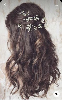 the back of a woman's head with long hair and flowers in her hair