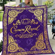 a woman holding up a purple and gold crown royal blanket in front of her house