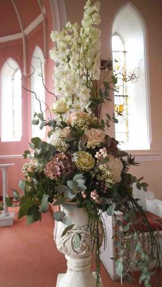 a vase filled with lots of flowers on top of a table next to a window