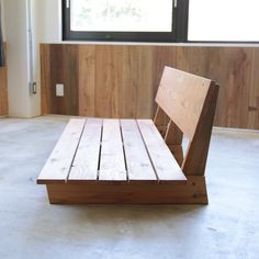 a wooden chair sitting on top of a floor in front of a window with wood slats