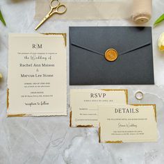 the wedding stationery is laid out on top of the table, including an envelope with a gold seal