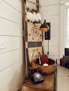 an old fashioned telephone sitting on top of a wooden table next to a wall hanging