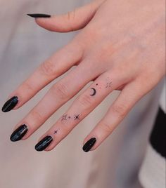 a woman's hand with black nail polish and tattoos on her left index finger