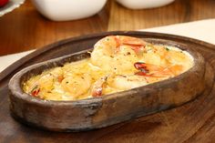 a wooden bowl filled with shrimp on top of a table next to bowls of food