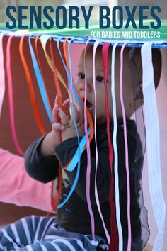 a baby sitting on top of a wooden floor next to colorful streamers hanging from the ceiling