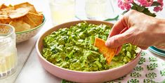 a person dipping chips into a bowl of guacamole