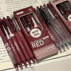 several pens are lined up in a row on top of an open book with the same pen