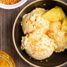 two bowls filled with ice cream on top of a wooden table next to some fruit