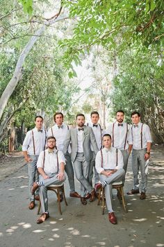 a group of men standing next to each other on top of a wooden chair in front of trees