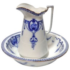 a blue and white porcelain pitcher on a saucer with a matching plate in the shape of a bowl