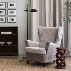 a living room with a chair, book shelf and pictures on the wall above it