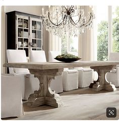 a dining room table with white chairs and chandelier