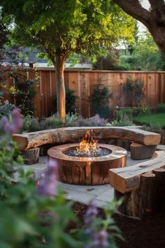 a fire pit surrounded by wooden benches and trees in a backyard with purple flowers on the ground