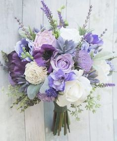 a bouquet of flowers sitting on top of a white wooden table next to a wall