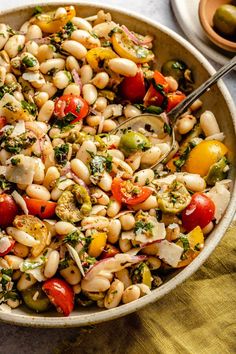 a bowl filled with beans and vegetables on top of a table next to a fork