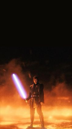 a man holding a light saber standing on top of a snow covered ground