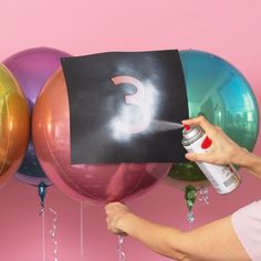 a woman spray painting balloons with the letter c on it