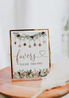 a sign that says favors please take one sitting on top of a wooden table next to a feather